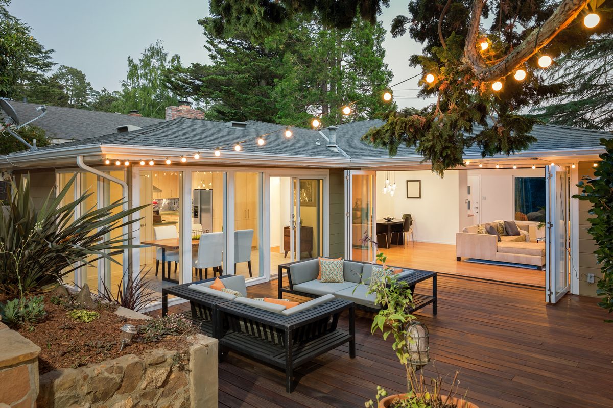 Folding glass patio doors open to a lit deck at dusk