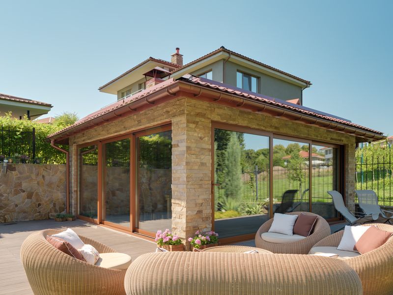 Glass enclosed sunroom with sliding panels off a stone patio