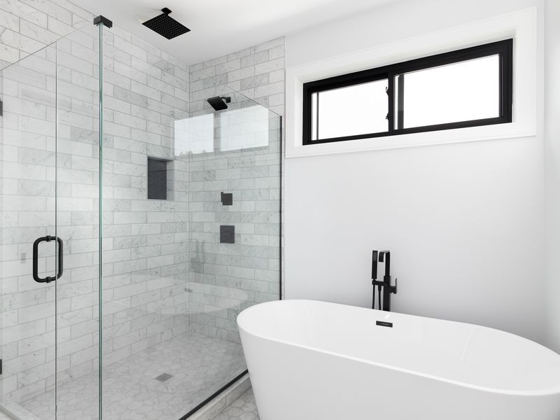 Frameless glass shower enclosure with marble tile