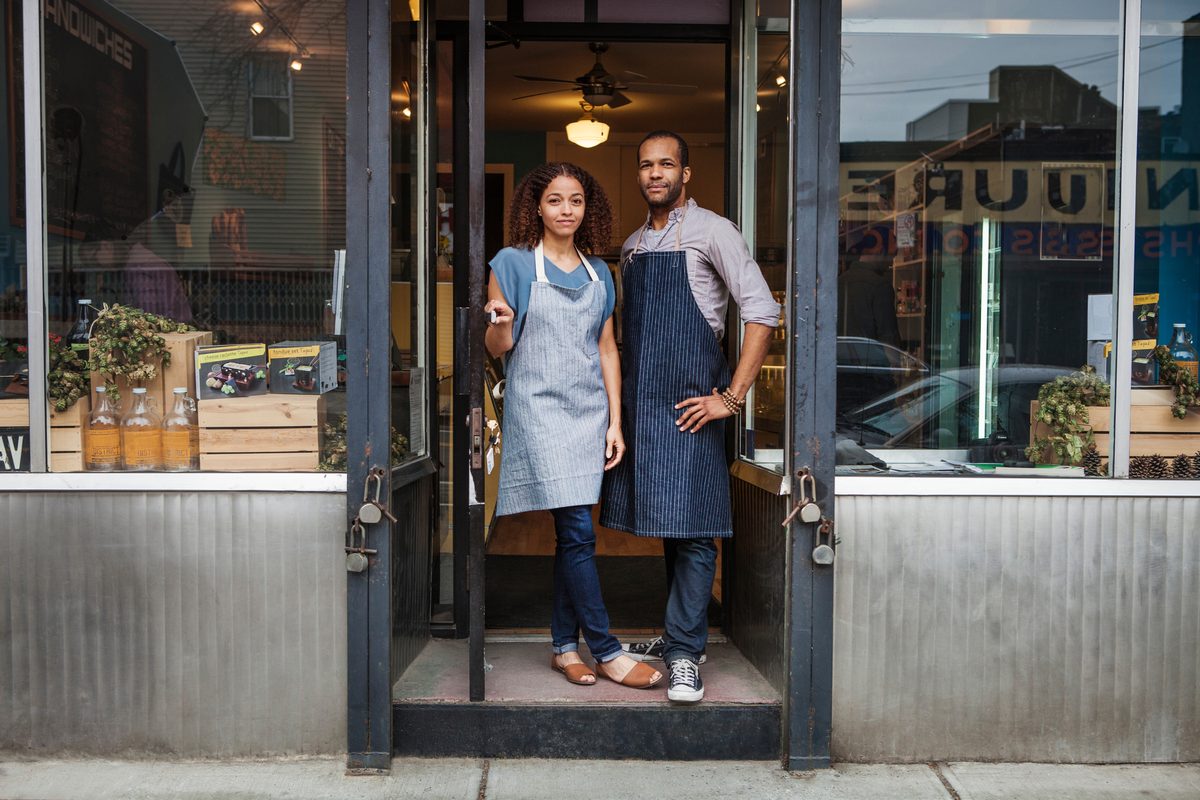 Two shop owners standing in the doorway of their storefront